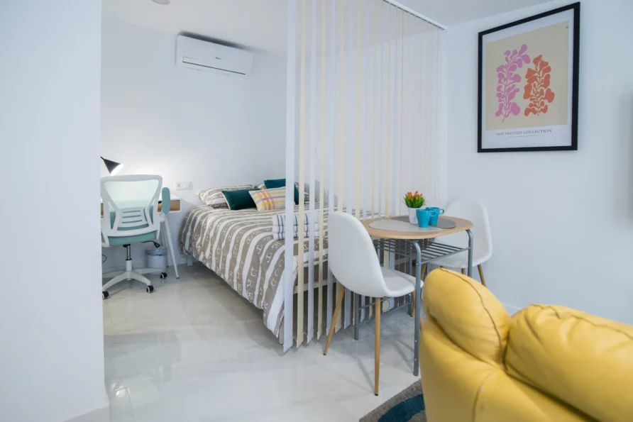 Cozy studio apartment with bed, desk, and dining area