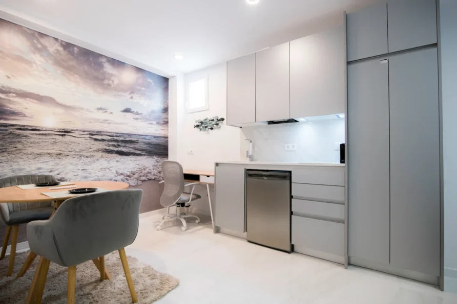 Modern studio apartment with beach mural and compact kitchen