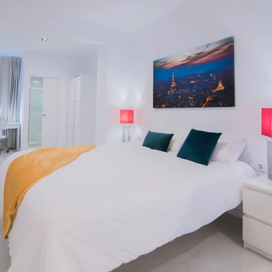 Bright modern bedroom with white bed and teal pillows