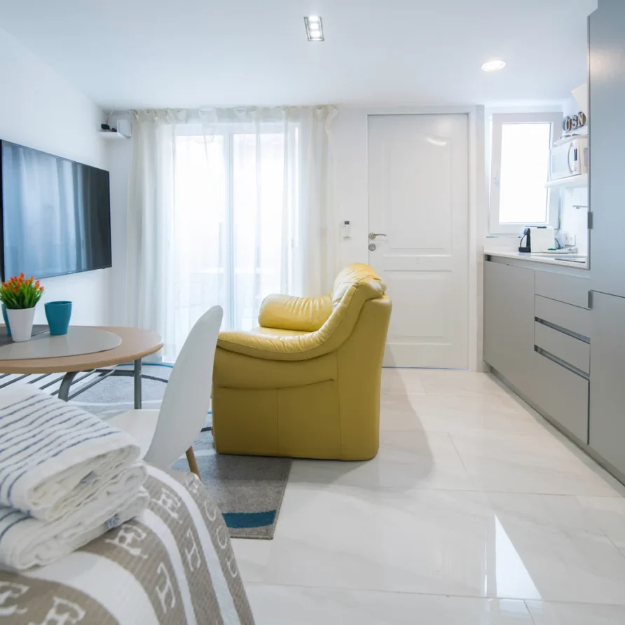 Modern studio apartment with bed, kitchen, dining, and yellow chair