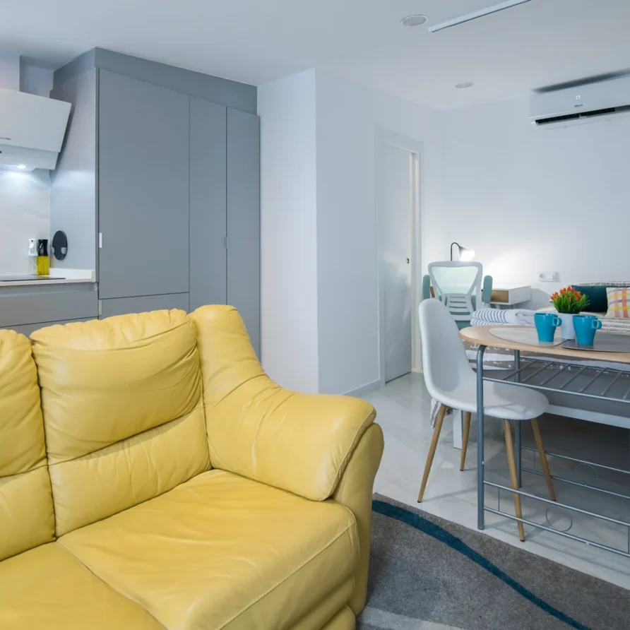 Modern living space with yellow sofa & kitchen