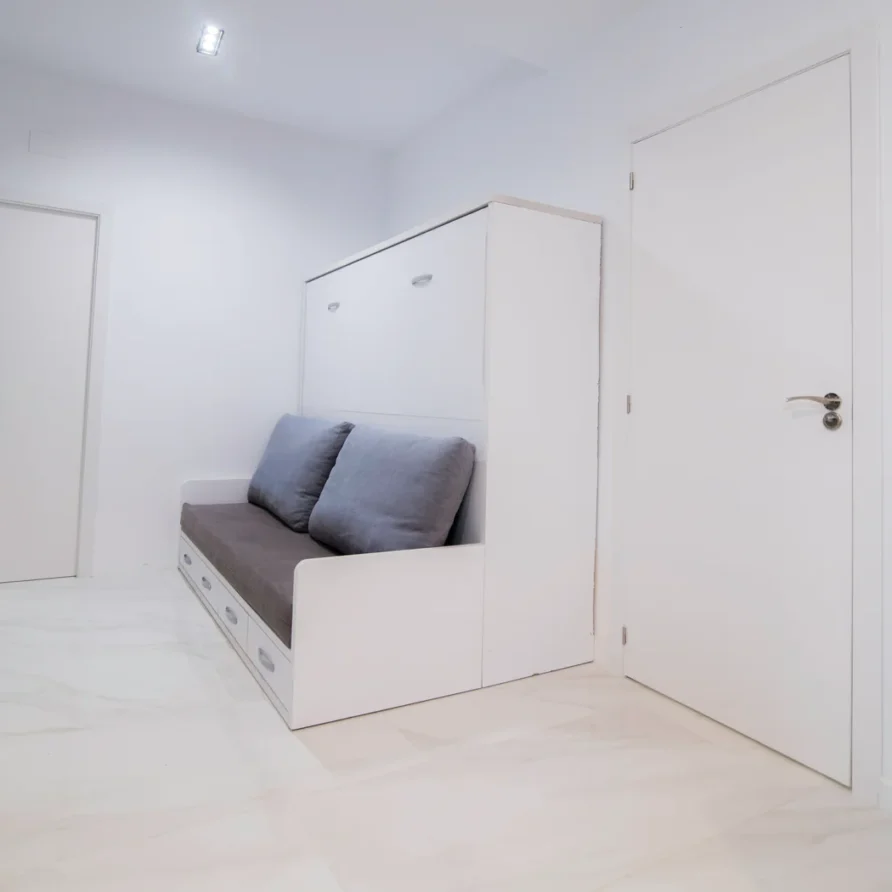 White room with a pull-out sofa bed and two closed doors