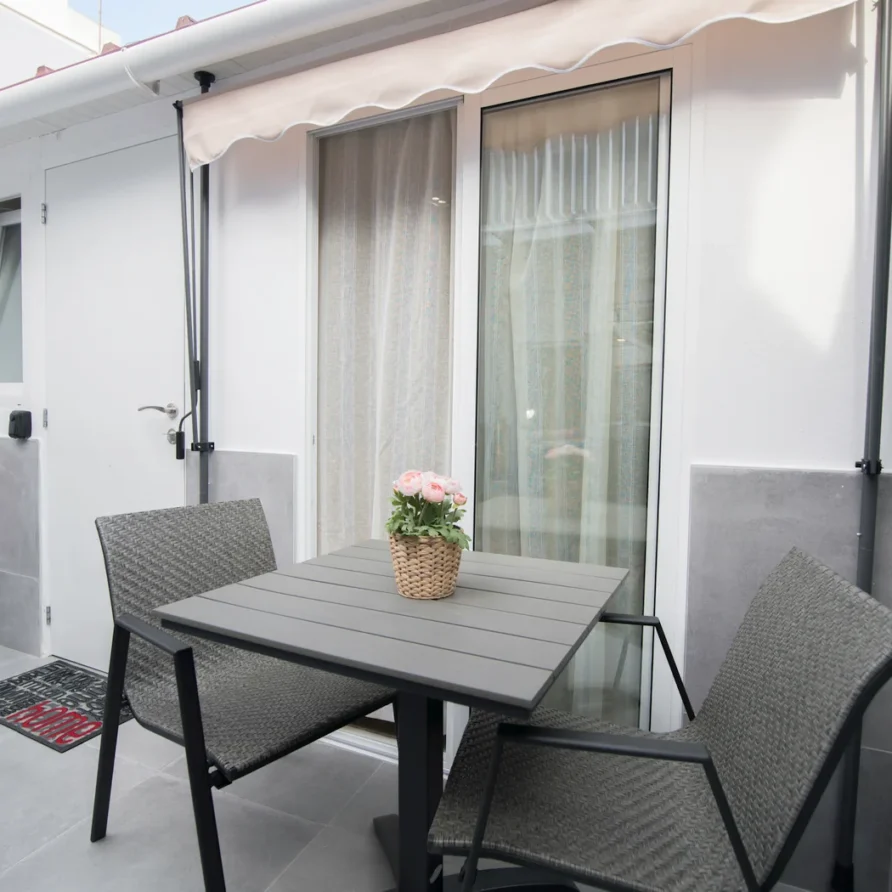 Outdoor patio with table, chairs, and potted flowers on a sunny day
