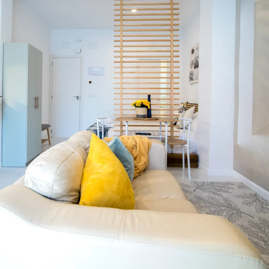 Cozy living room with white couch, yellow pillows, dining area