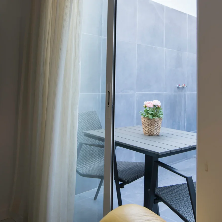 Balcony with table, chairs, and potted pink flowers