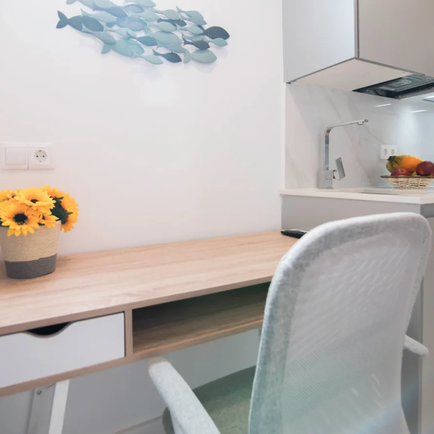 Desk with sunflowers, white chair, and fish wall art in a room