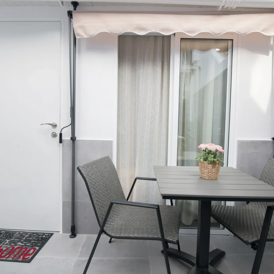 Small patio with table, chairs, and pink flower