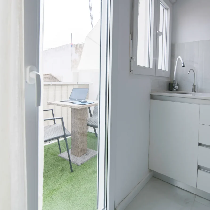 Balcony with chairs, table, laptop and kitchen view