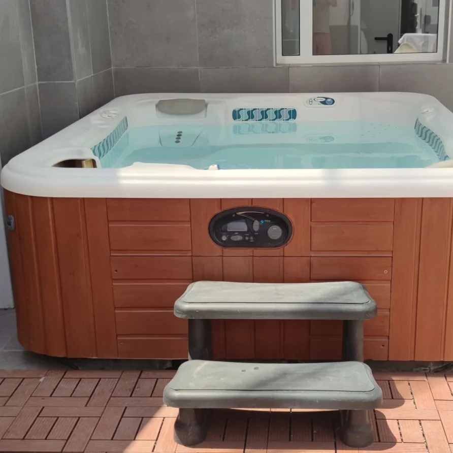 Hot tub with wooden base and steps on patio