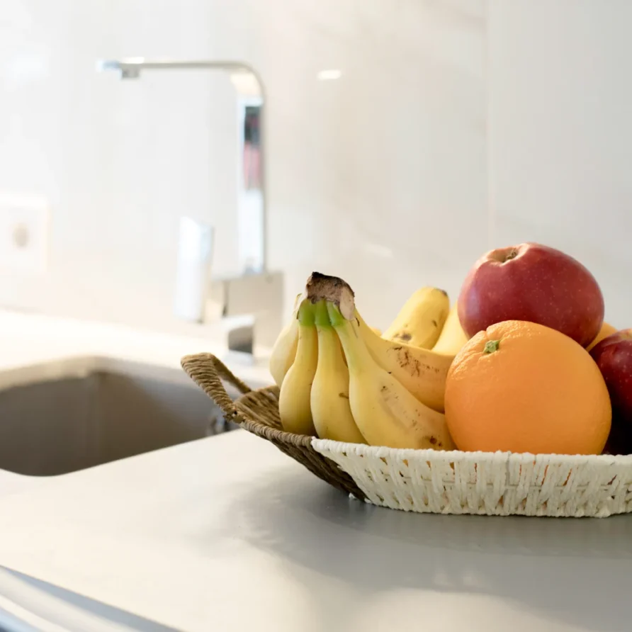 Fruit basket with bananas, apples, and an orange on a counter