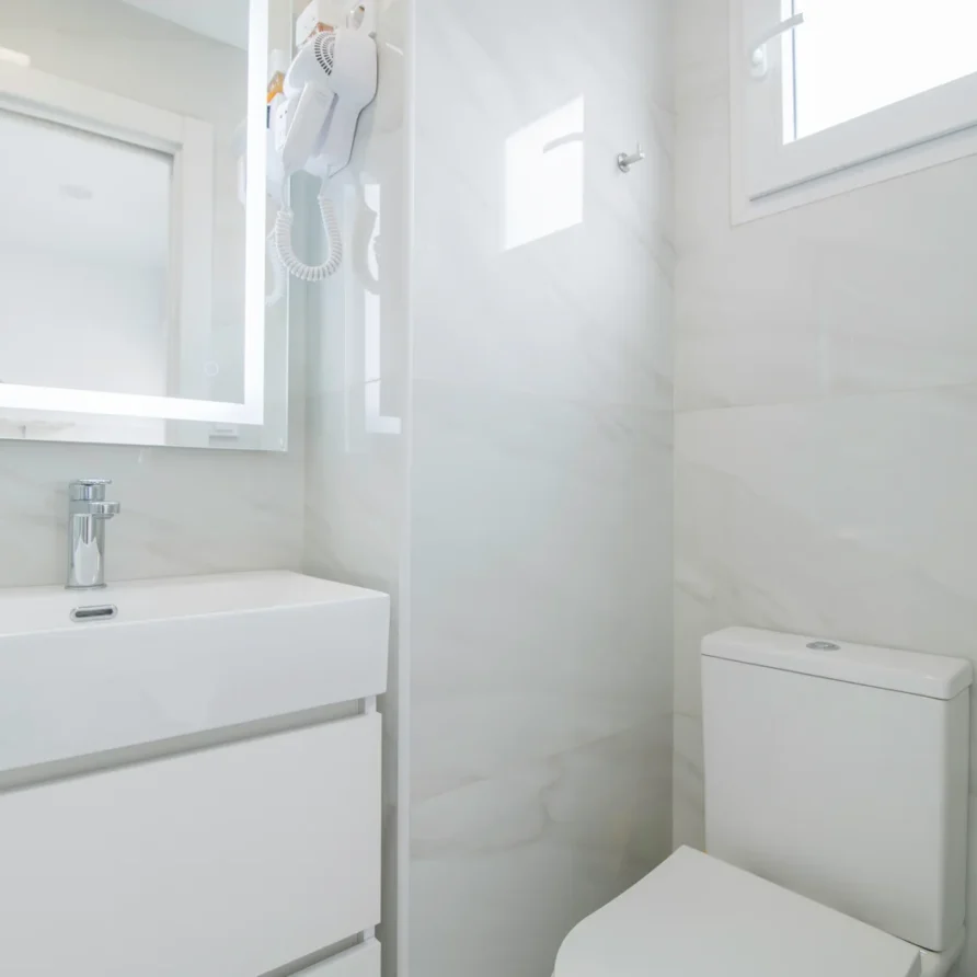 Modern white bathroom with sink, mirror, and toilet