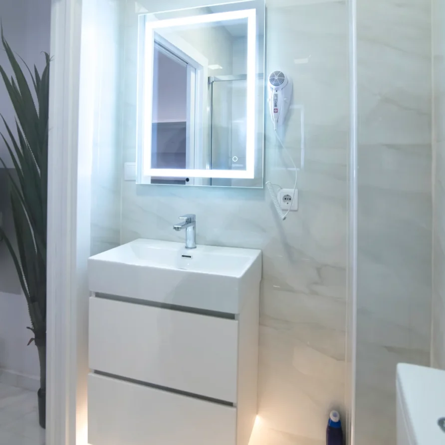 Modern bathroom with white vanity, sink, and lighted mirror