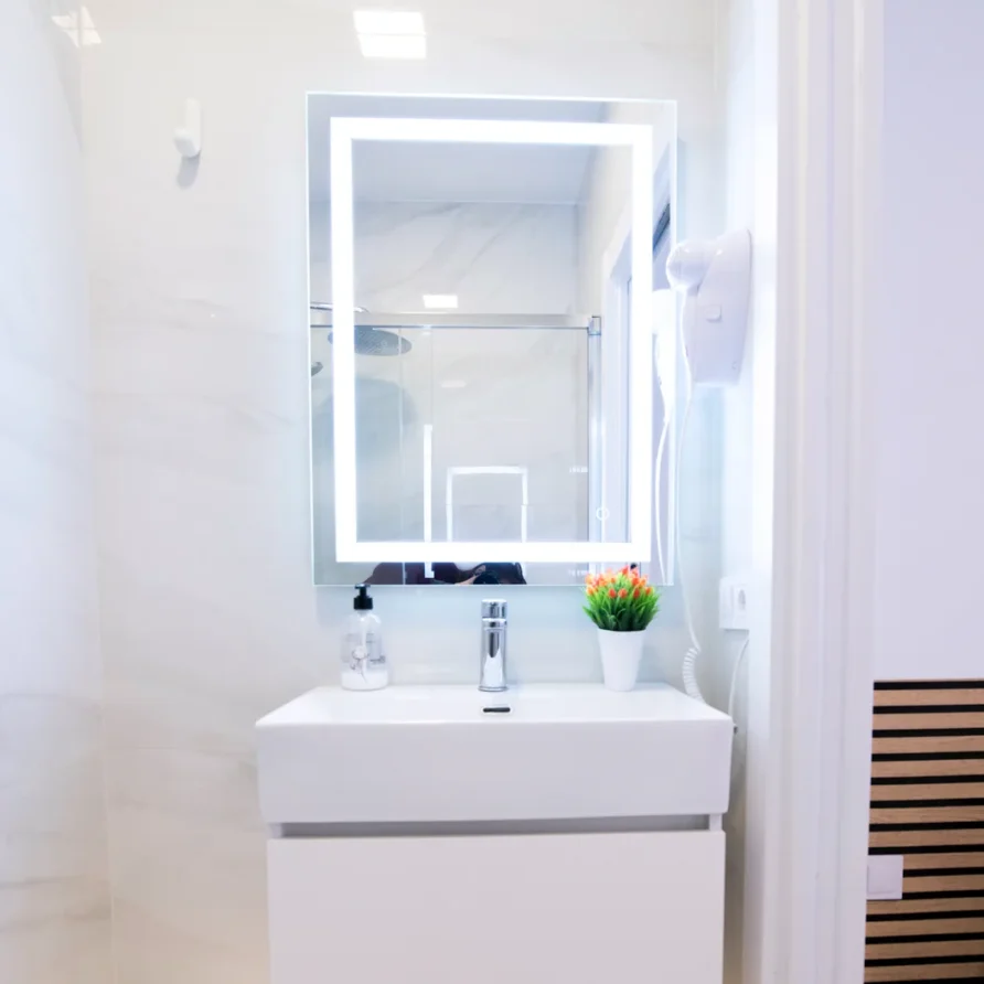 Modern bathroom with lighted mirror, white vanity, and sink