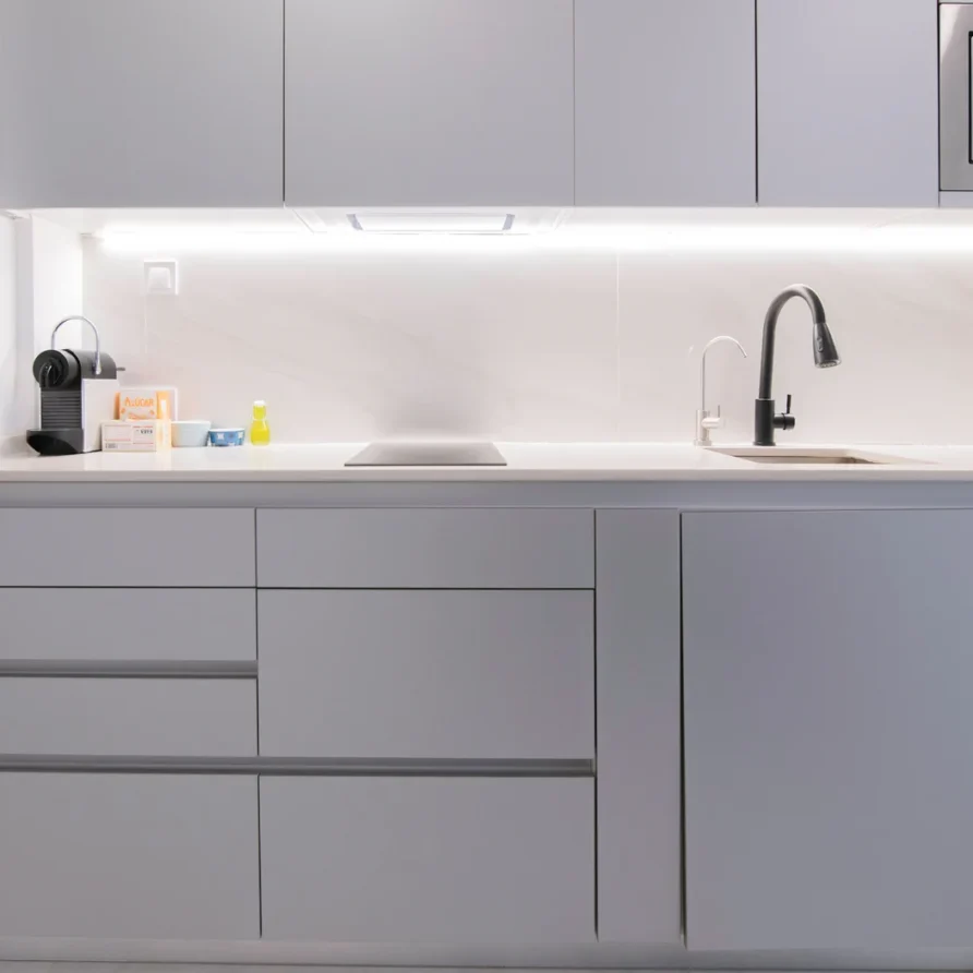 Modern light grey kitchen with white countertop, sink, coffee machine