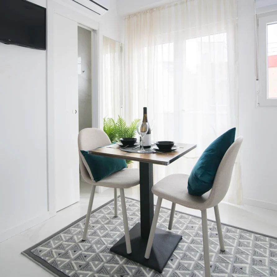 Cozy dining nook with small table, two chairs, wine, and greenery